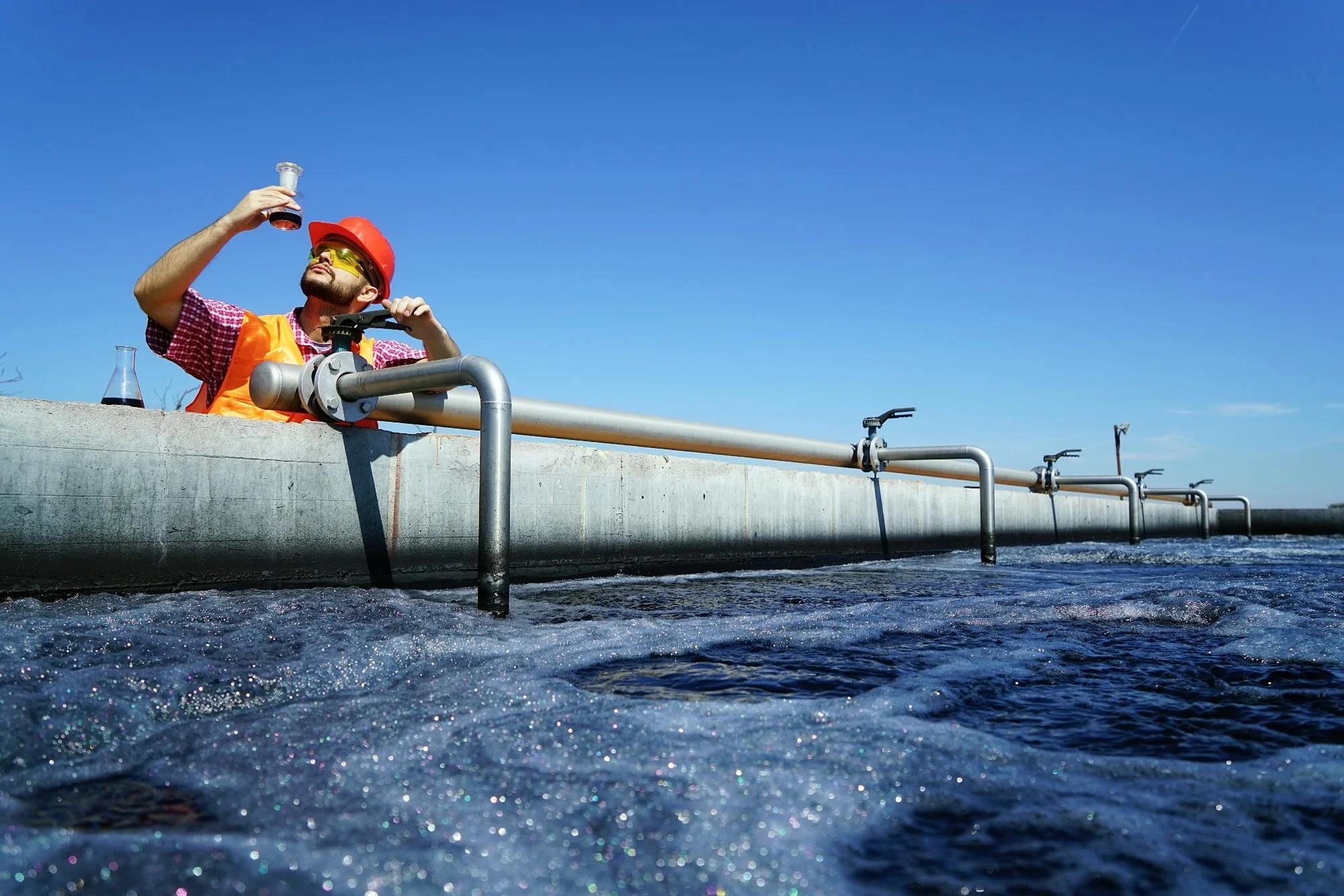 Technician inspecting pipework at a wastewater treatment plant
