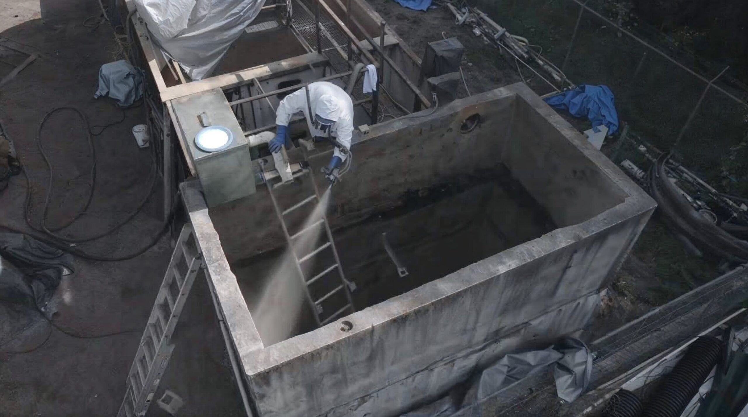 Applicator spraying ArmorThane polyurea inside a concrete water treatment tank