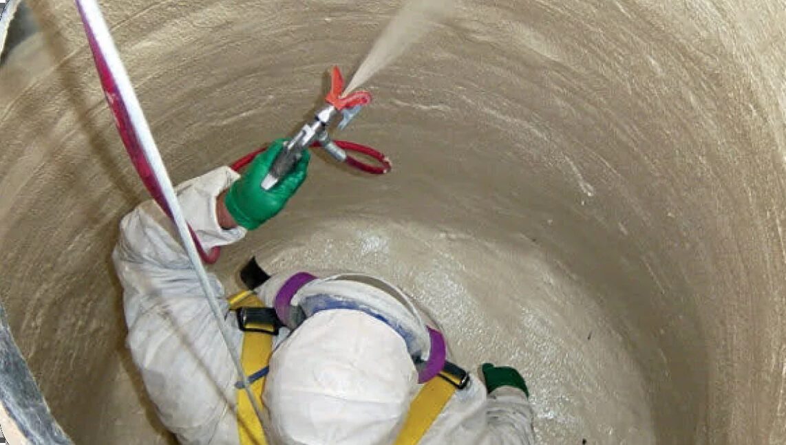 Applicator spraying a manhole interior from above